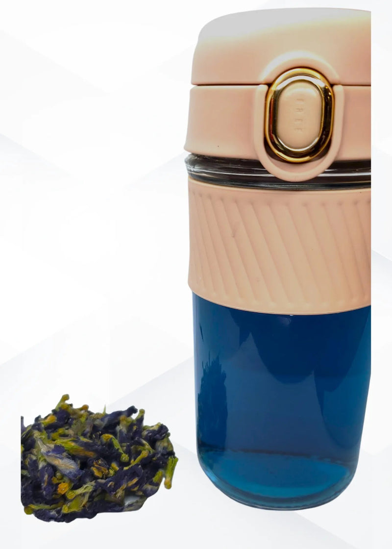 brewed tea showing blue color and beige top, accompanied by loose tea leaves on a white background.